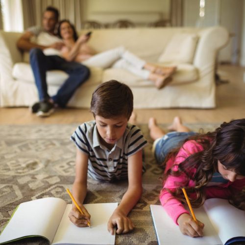 Kids doing homework while lying on rug Kids doing homework while lying on rug